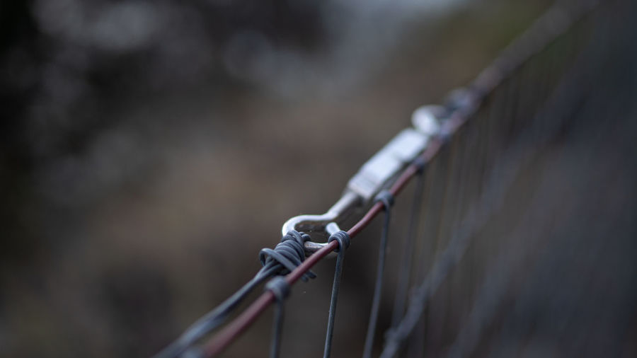 Close-up of metal fence against bridge