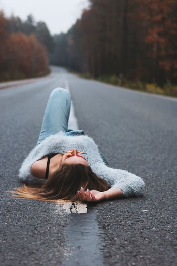 Young woman laying on the empty country road 