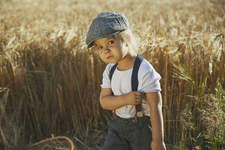 Adorable sad street child in a field at sunset
