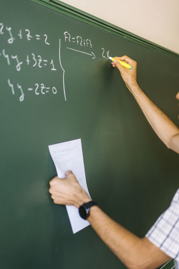Math teacher writing on chalkboard in classroom
