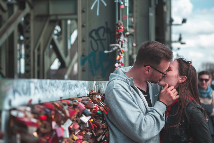 Couple kissing by love locks on bridge in city
