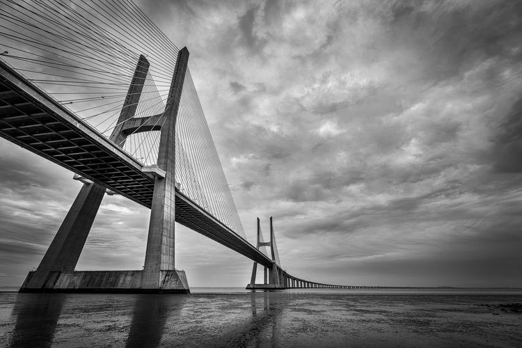 Low angle view of bridge over sea against cloudy sky