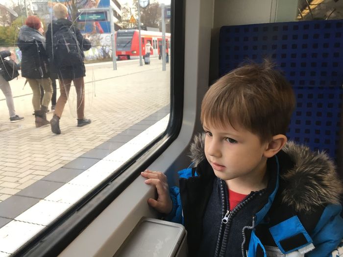 Cute boy looking through window while sitting in train