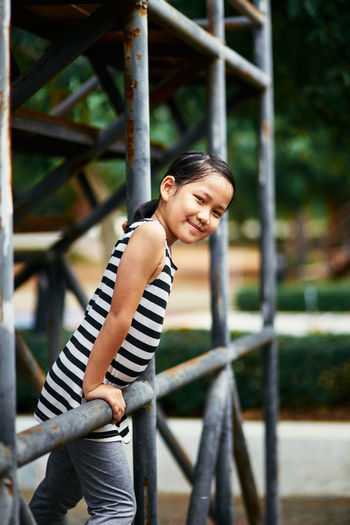 Portrait of young woman standing against railing