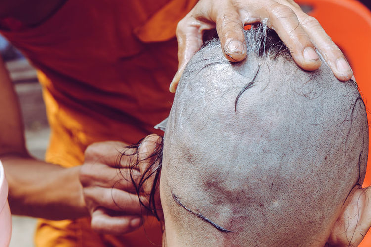 Midsection of monk cutting males hair