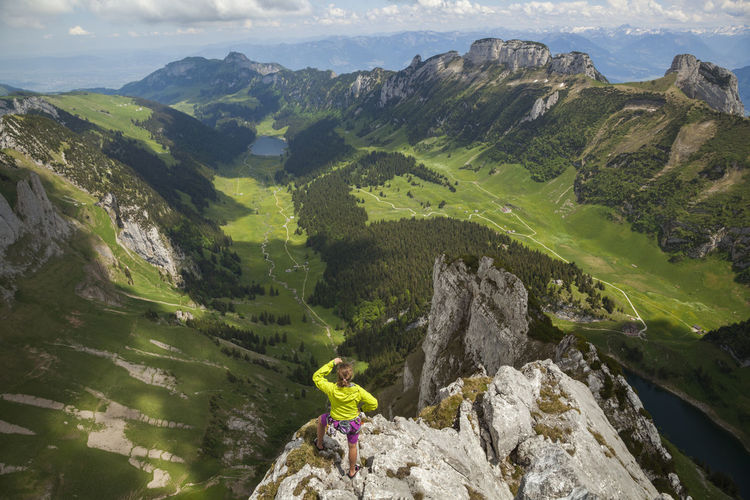 Rock climber on summit over valley, alpstein, appenzell, switzerland