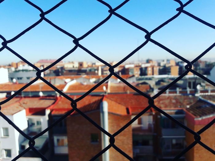 Full frame shot of chainlink fence against buildings in city