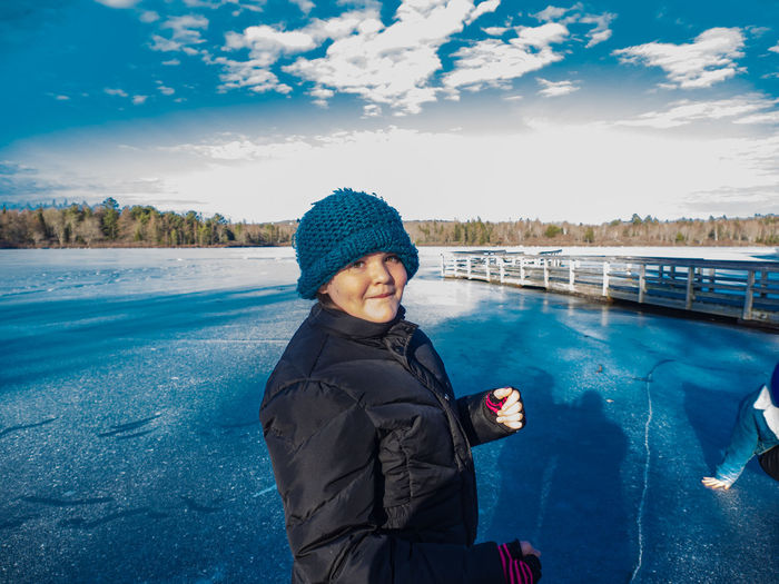 Portrait of girl standing on frozen land against sky