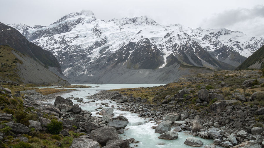Glacier stream flowing from under majestic snowy mountain, aoraki mt cook national park, new zealand