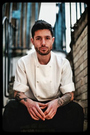 Portrait of confident chef sitting outside building