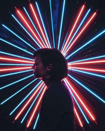 Full length of boy standing against illuminated light painting at night