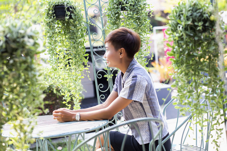 Side view of woman sitting on plants