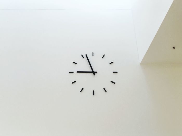 Low angle view of clock on white wall
