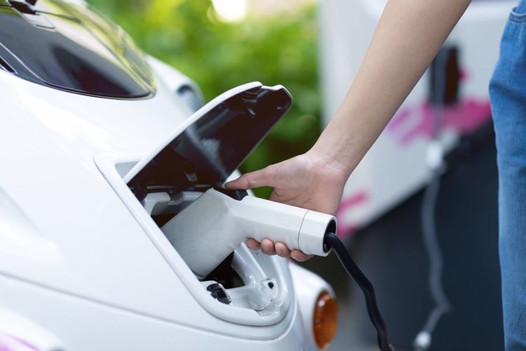 Midsection of woman charging electric car