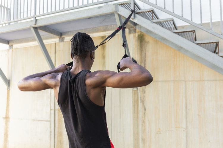 Man exercising with suspension straps hanging on staircase