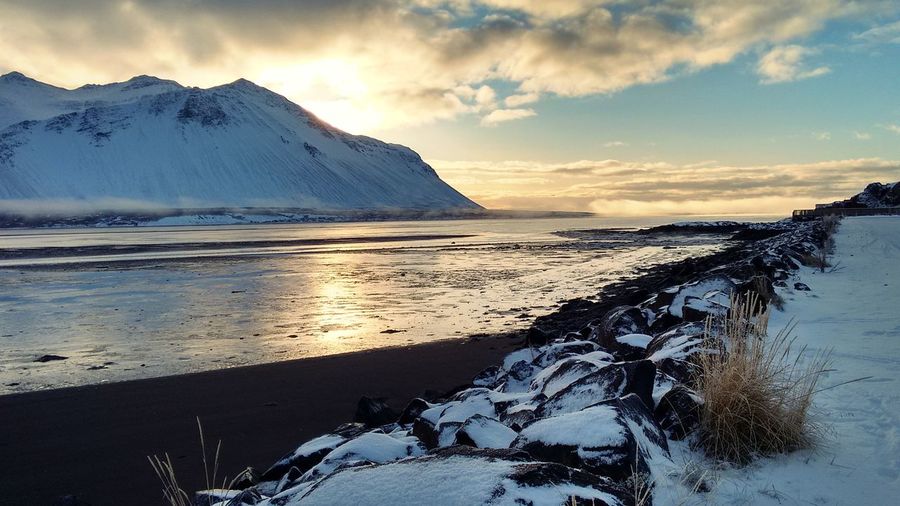 Scenic view of mountain by sea against sky during winter