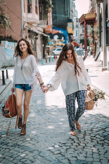Two hippie women friends walking on a sunny day with a backpack and a basket.  freedom and summer