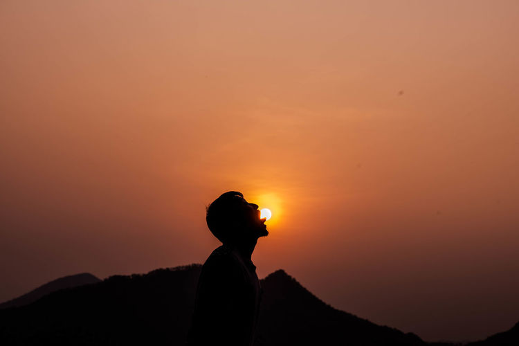 Optical illusion of man licking sun at sunset