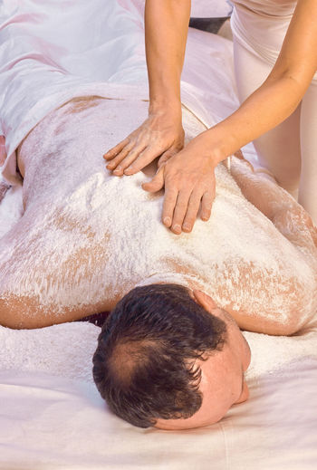 A woman healer performs a ritual with salt, rubs the back of a lying man with salt. relaxation