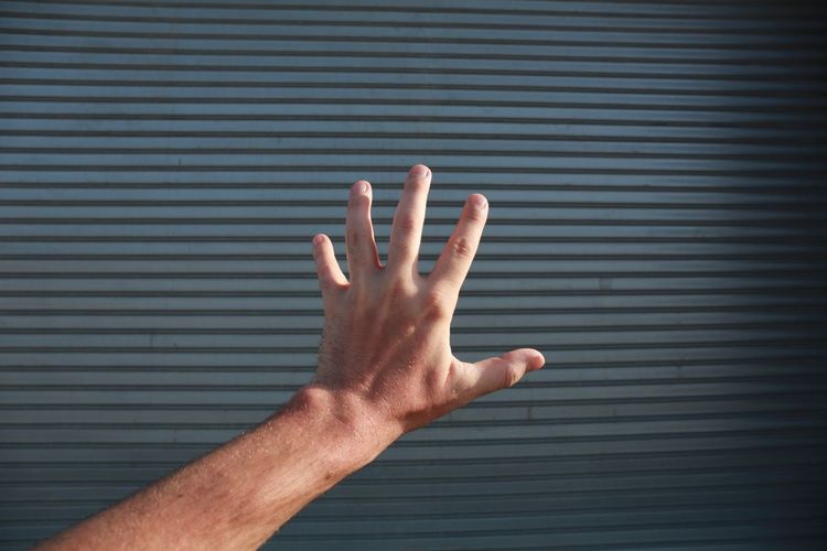 Cropped image of hand against closed shutter