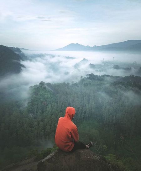 Rear view of man looking at mountains against sky