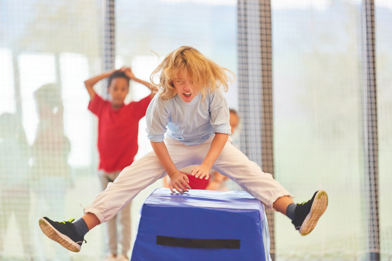 Girl jumping over box at school gymnasium