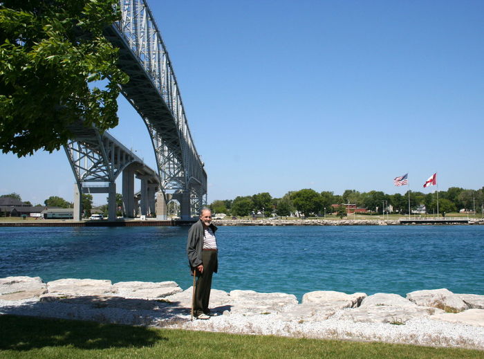 Man standing on pavement against bridge at port huron