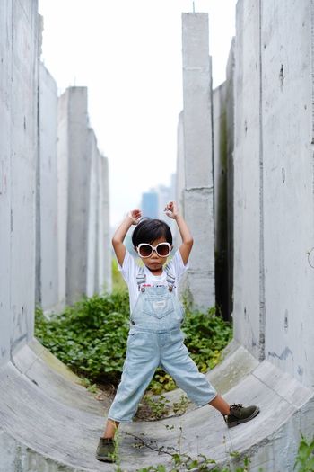Cute girl wearing sunglasses while standing amidst built structure
