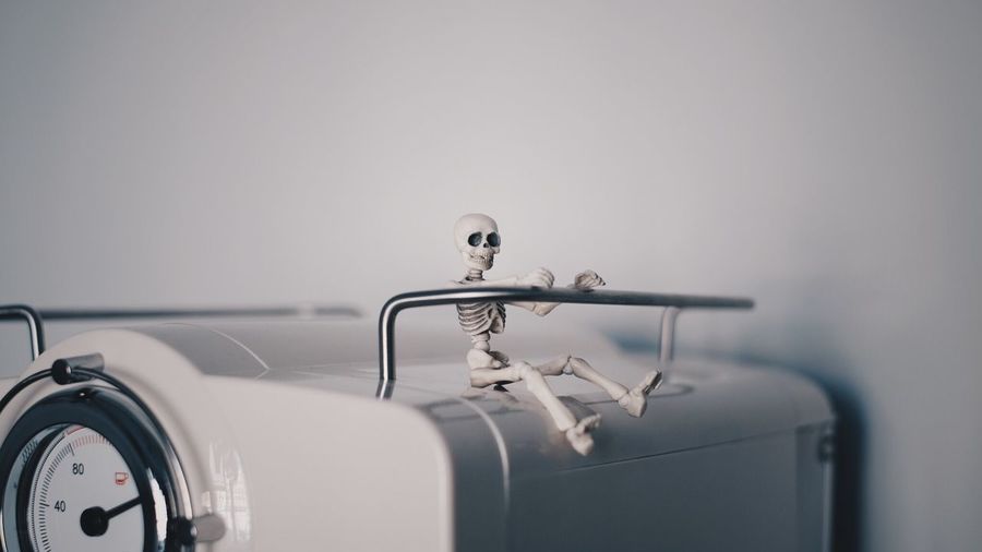 Close-up of toy skeleton on machine against white wall