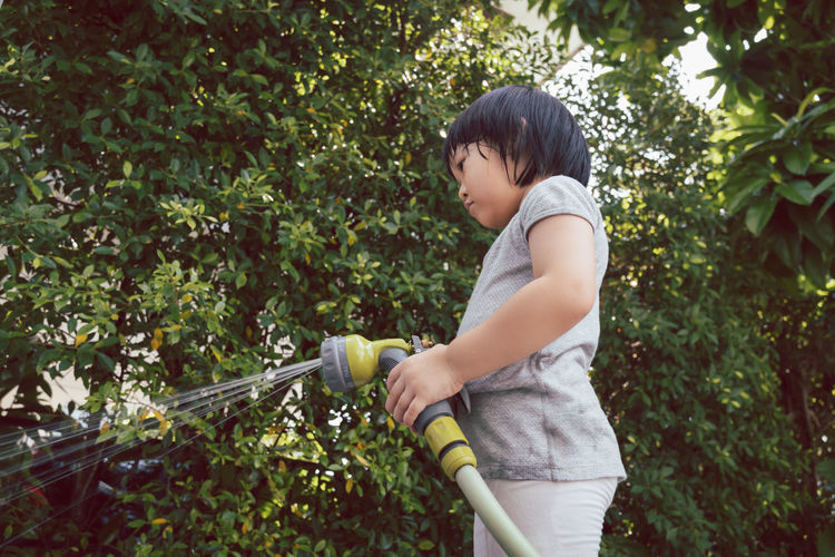 Cute girl holding garden hose outdoors