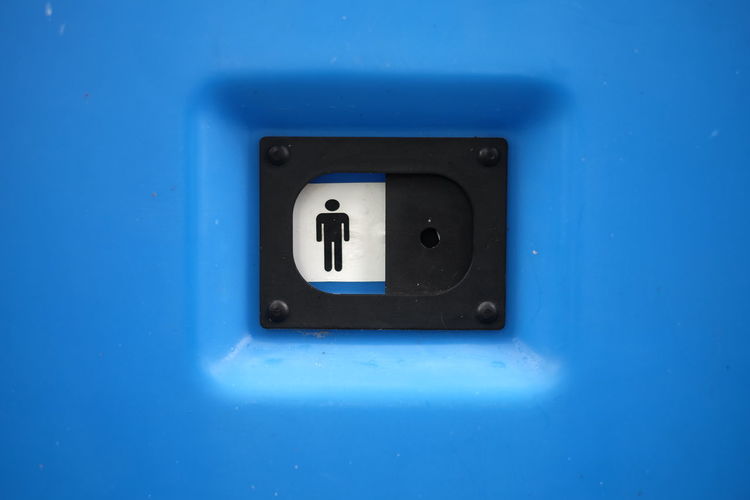 Close-up of mens room sign on blue door