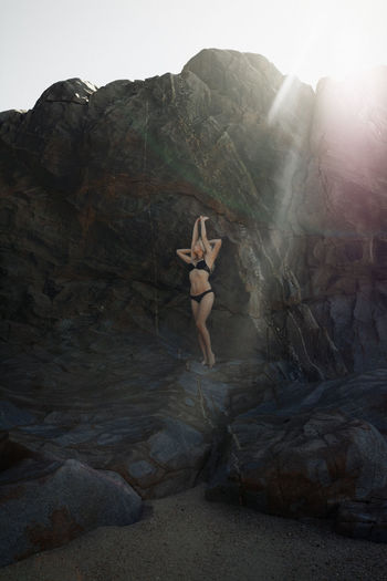 Double exposure of woman in bikini standing on rock at beach