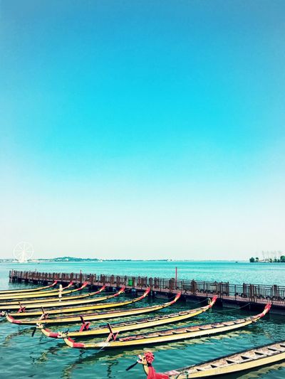 Row of longtail boats moored in sea against sky