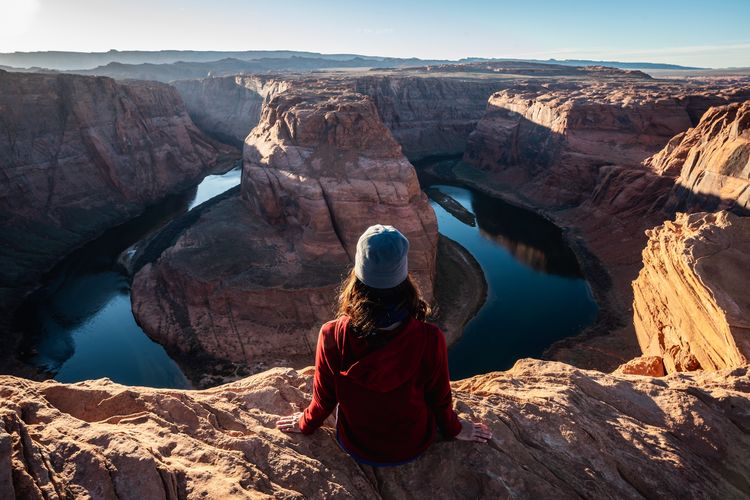 Rear view of woman sitting at the edge horseshoe bend