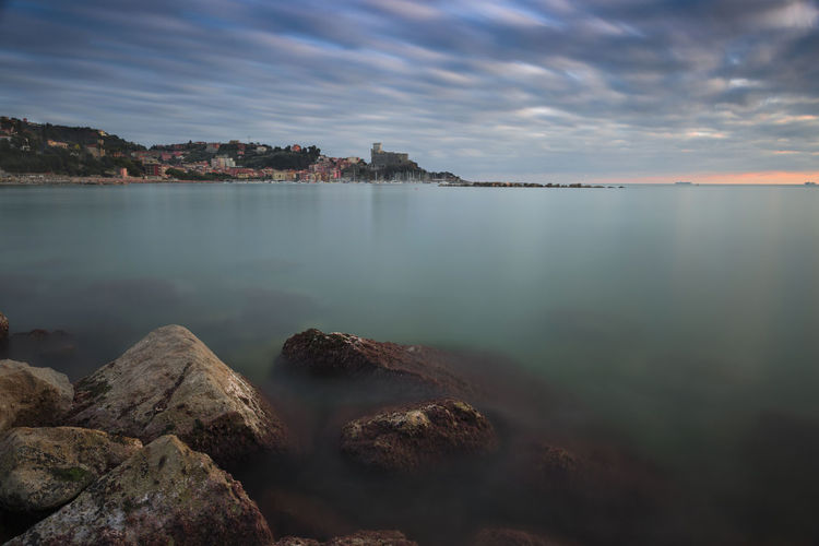 Scenic view of sea against cloudy sky during sunset