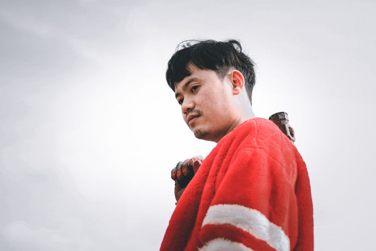 Portrait of young man looking away against white background
