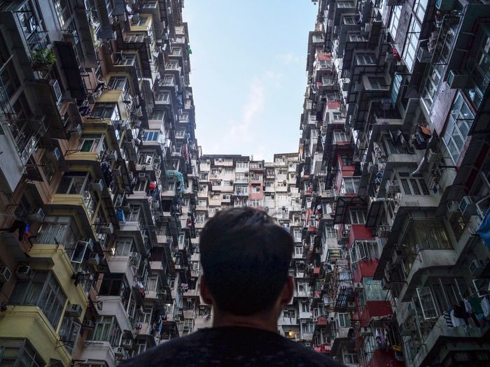 Low angle view of man standing amidst residential buildings