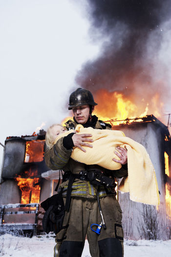 Fireman holding rescued girl, burning building in background