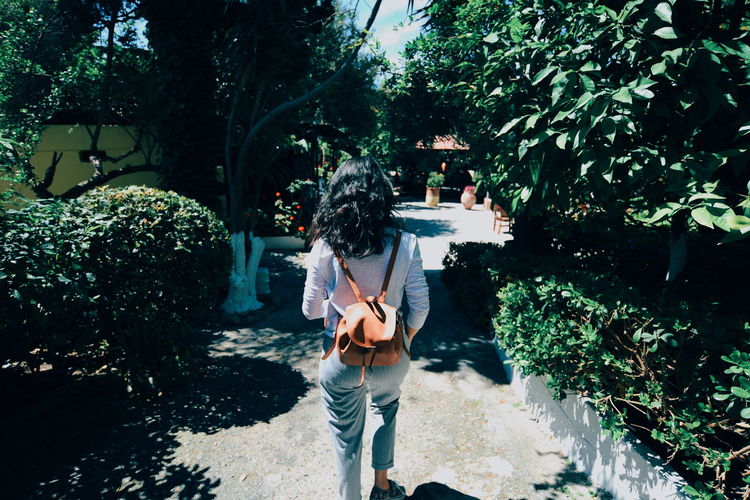 Rear view of woman with backpack walking amidst plants