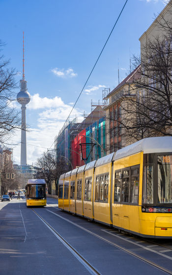 Tram on street amidst buildings in city against sky