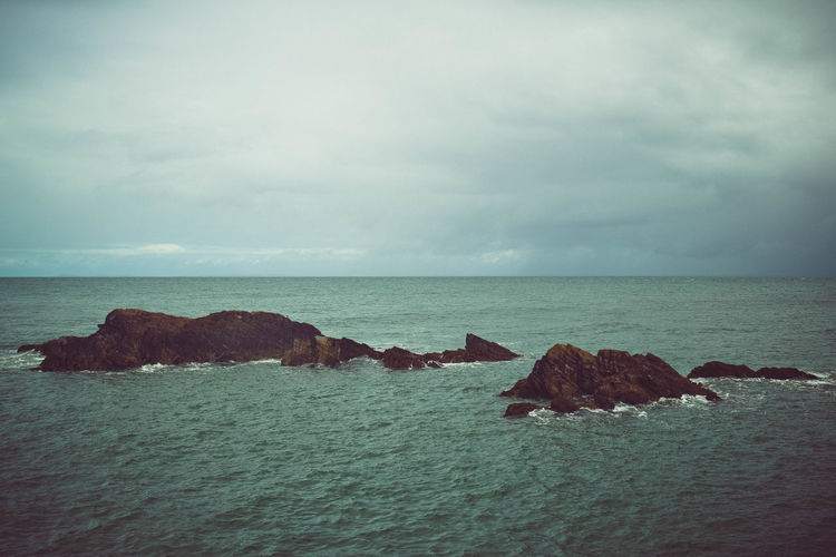 Rocks on sea shore against sky