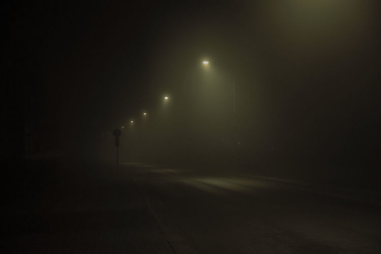 Empty road in illuminated city at night