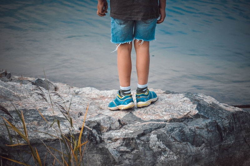Low section of child standing on rock