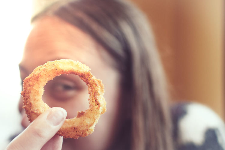 Close-up portrait of woman holding onion ring