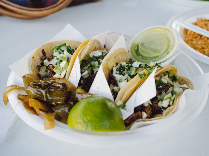 Close-up of fresh tacos served with lemon in plate on table