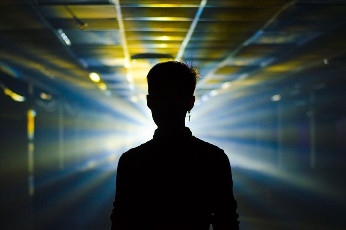 SILHOUETTE MAN STANDING IN ILLUMINATED TUNNEL
