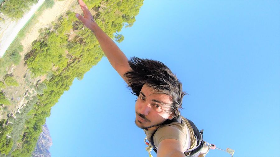 Low angle view of man bungee jumping against blue sky