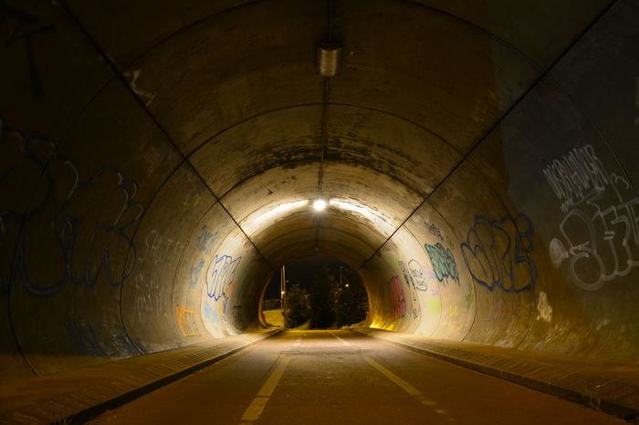 Empty road in illuminated tunnel at night
