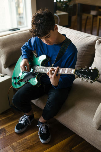 Teen boy practicing electric guitar at home