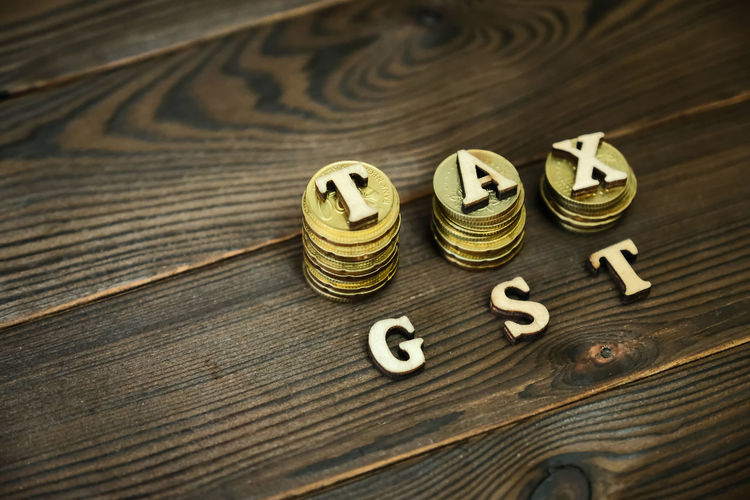 High angle view of coins with tax and gst text on table